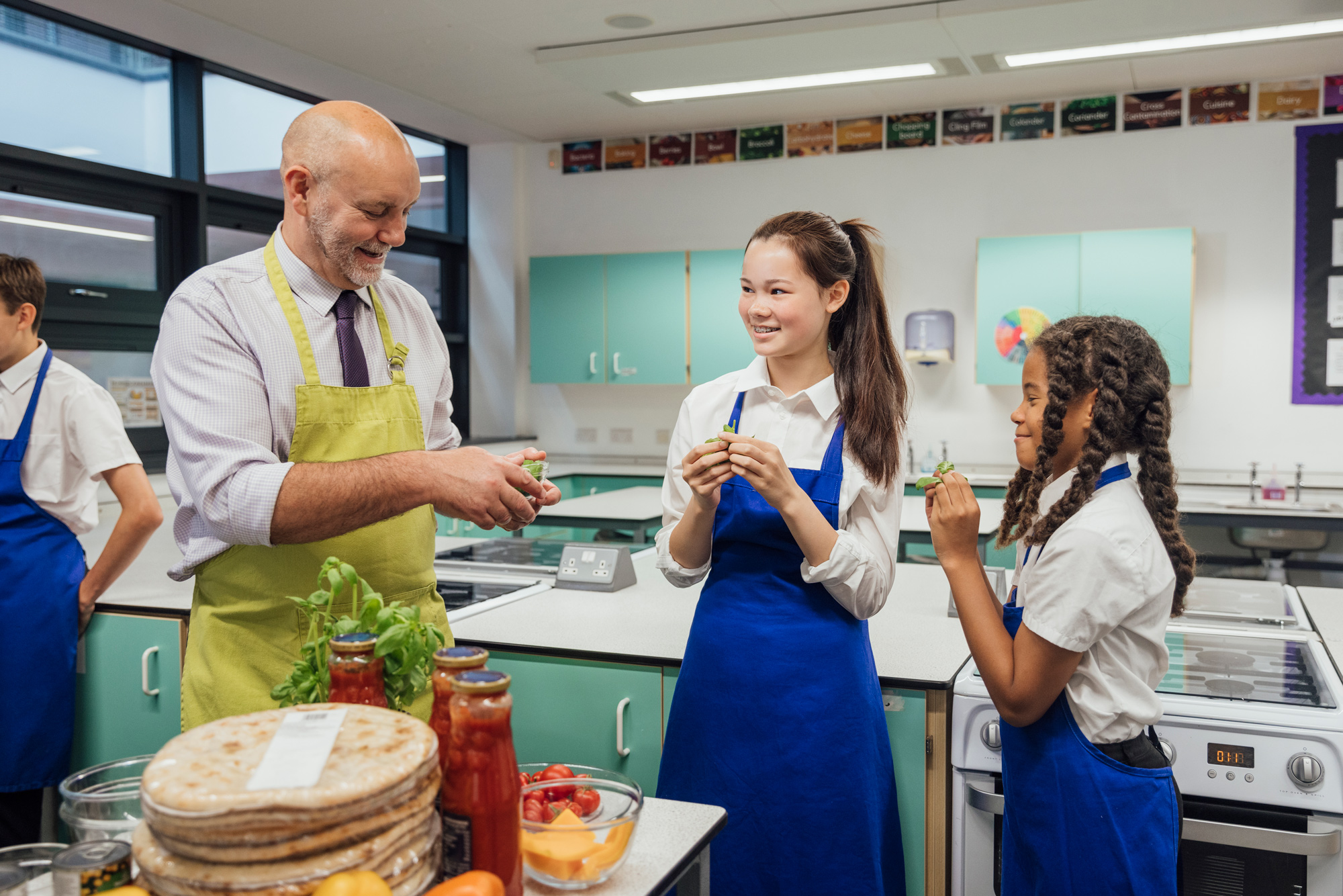 Try Adding Into Food A side view of a cooking class and the students learning which fresh herbs and veg they are going to be adding to the pizzas they are making from scratch in class in a school they attend in the North East of England. One of the students is pulling a face after tasting the herb. 