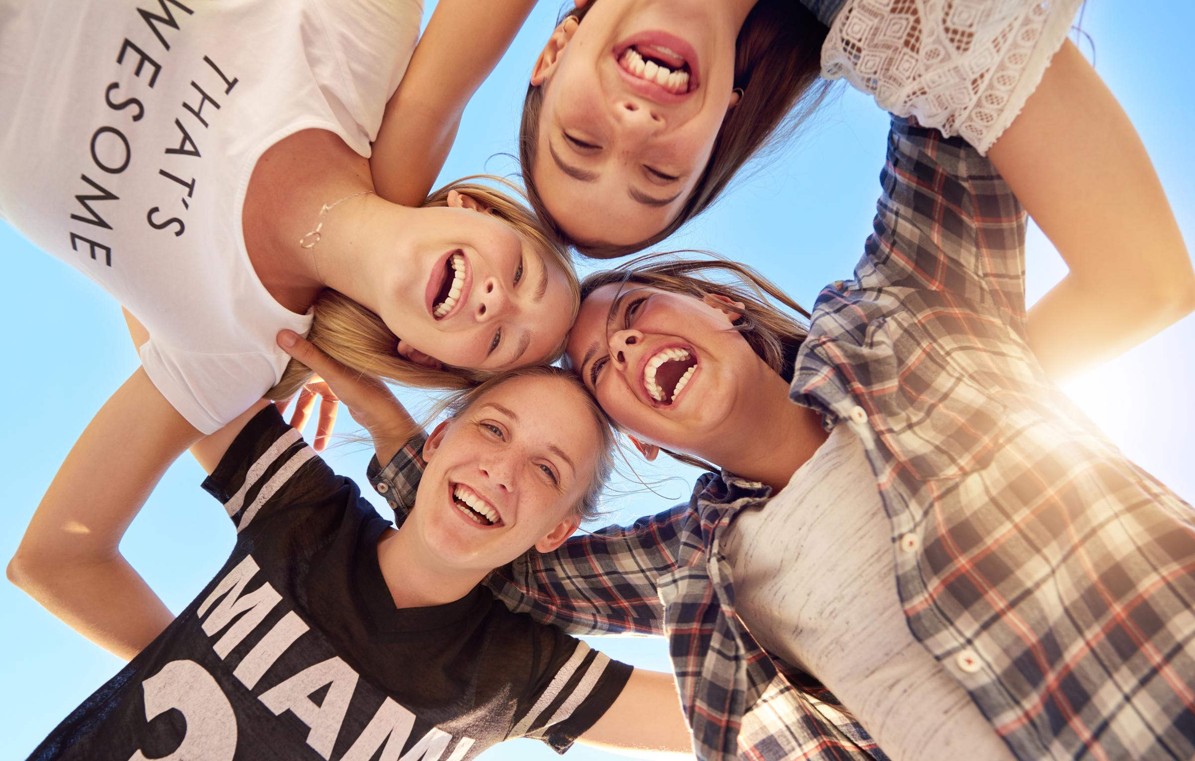 a group of adolescent girls in a huddle smiling and laughing