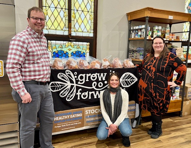 three individuals holding holiday hams