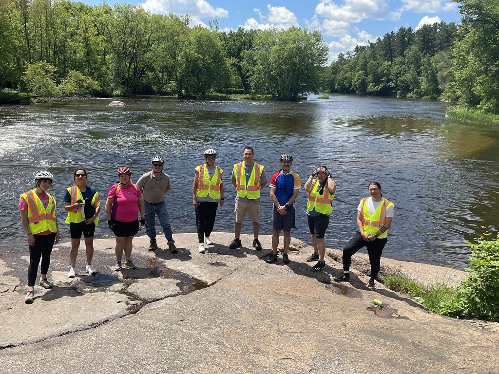 People in reflective vests standing in front of a river.