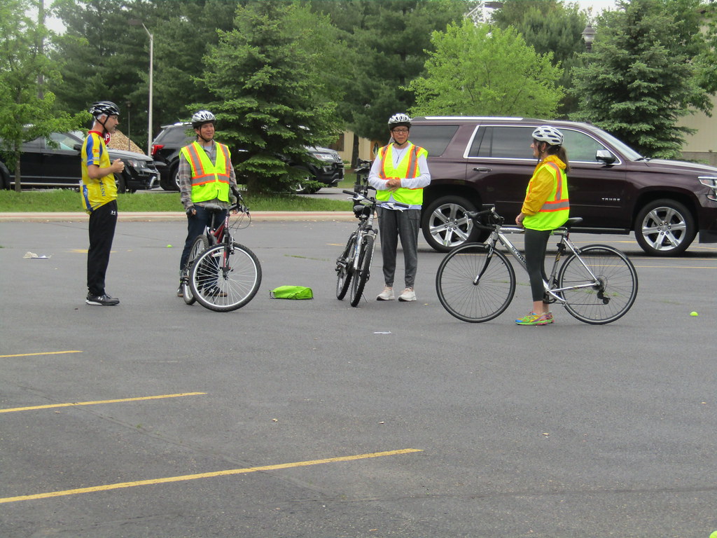 People in a parking lot with bikes, helmets, and reflective vests.